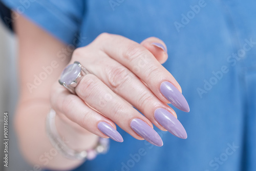 Female hand with long nails and a lilac nude nail polish