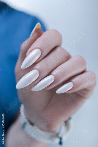 Woman's hands with long nails and a light white color nail polish