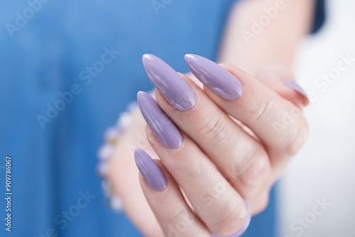 Female hand with long nails and a lilac nude nail polish photo