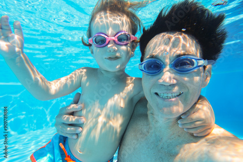 underwater photo of young dad with little boy in swimming pool