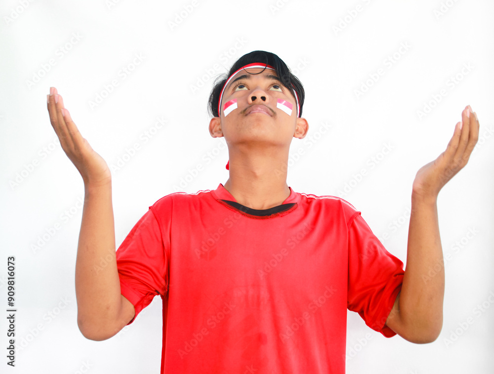 Asian Muslim man wearing independence shirt is praying and raising his head isolated on white background. Indonesian Independence day Asian Muslim man wearing independence shirt is praying and raising his head isolated on white background. Indonesian Independence day