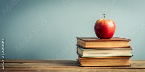 Stacked pile of vintage books with a crisp apple on top, conveying knowledge and academic achievement, set against a clean minimalist background with ample copy space.