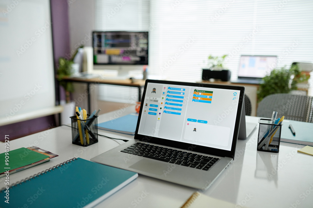 Spacious office featuring dual monitor setup with active work on laptop showing programming tasks while surrounded by organized workspace and desk accessories Spacious office featuring dual monitor setup with active work on laptop showing programming tasks while surrounded by organized workspace and desk accessories