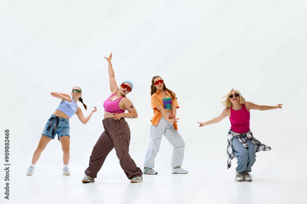 Obraz premium Girls dancing, dressed streetwear, with fun, energetic expression against white studio background. Fusion of modern dance with bold poses Concept of music, fashion and art, retro and modernity. Ad