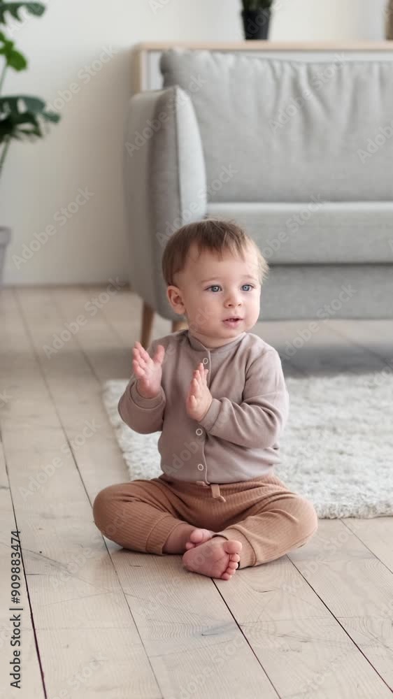 Excited Caucasian toddler boy clapping hand and jumping, sitting at home living room floor. Happy childhood concept. Vertical video. Excited Caucasian toddler boy clapping hand and jumping, sitting at home living room floor. Happy childhood concept. Vertical video.