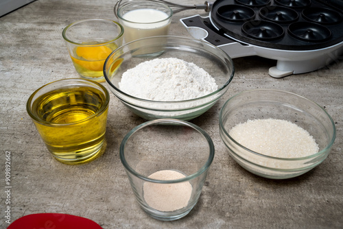 A table with several bowls of ingredients, including flour, sugar, and oil