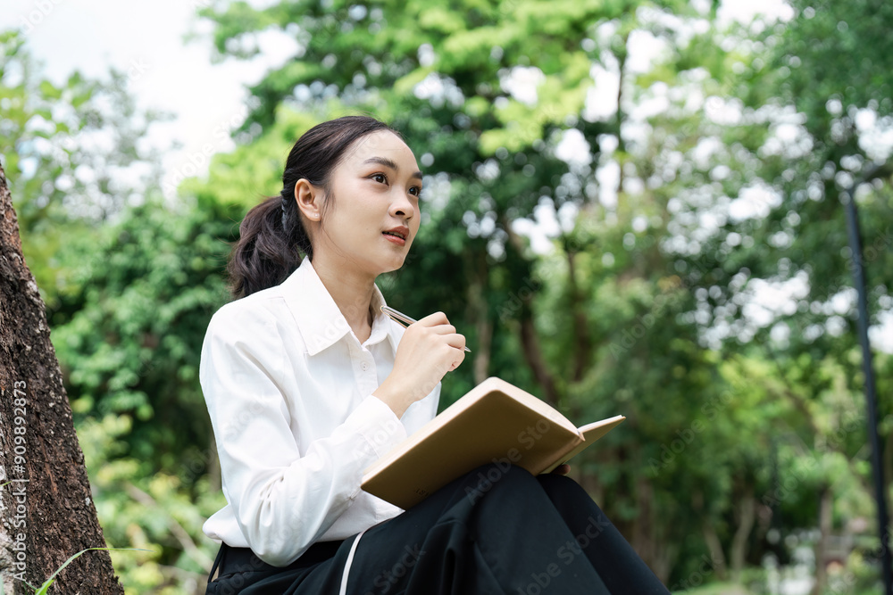 Young Professional Woman Working Outdoors with Notebook in Hand, Business Concept, Nature Background, Productive Work Environment Young Professional Woman Working Outdoors with Notebook in Hand, Business Concept, Nature Background, Productive Work Environment