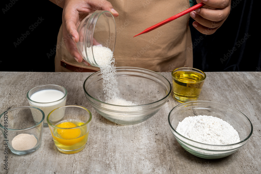A person is making a cake and has a bowl of sugar in front of them A person is making a cake and has a bowl of sugar in front of them