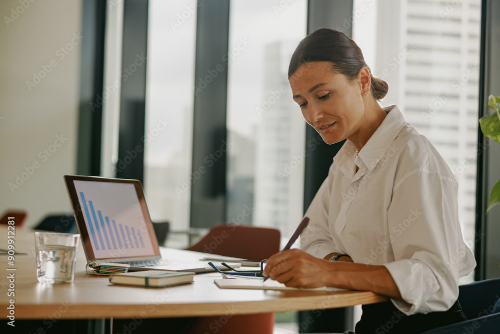 A Professional Businesswoman Deeply Engaged in Analyzing Data in a Modern Office Environment A Professional Businesswoman Deeply Engaged in Analyzing Data in a Modern Office Environment