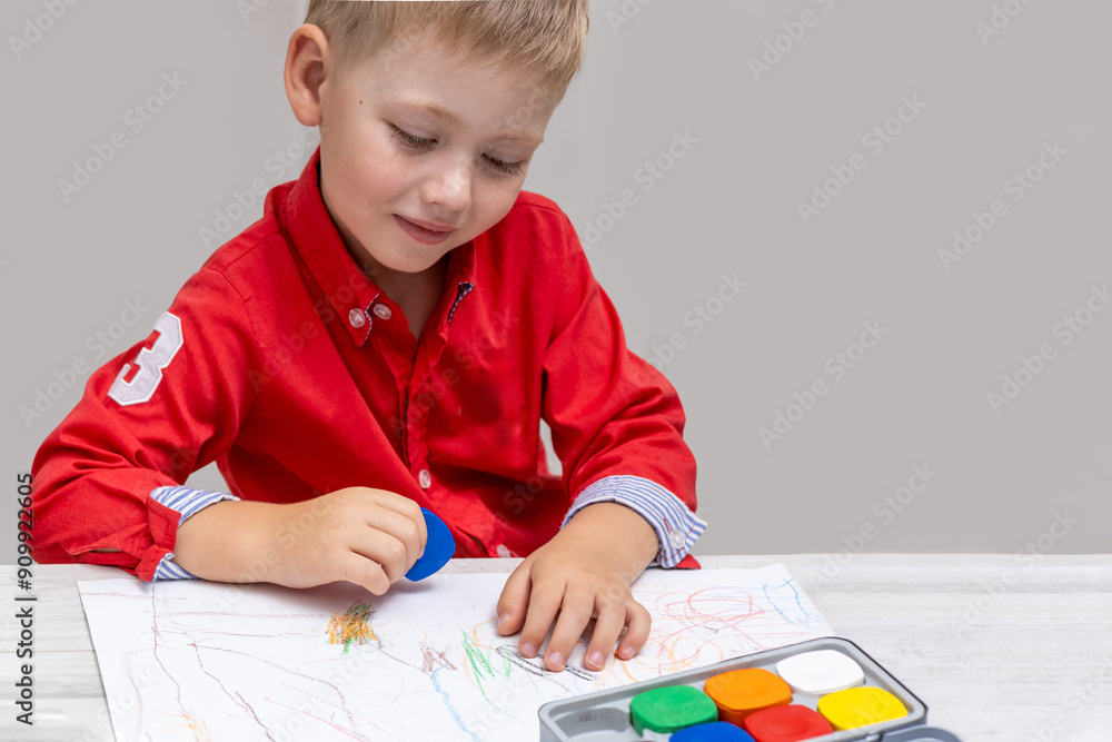 A toddler drawing with wax crayons on paper in a child's room, sitting at a table A toddler drawing with wax crayons on paper in a child's room, sitting at a table