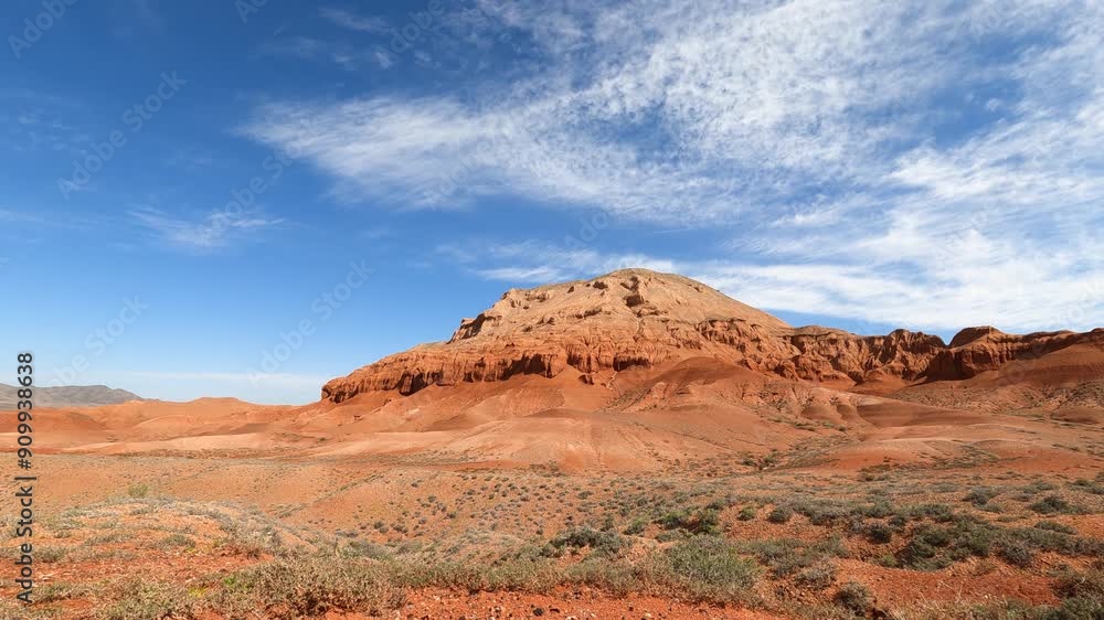 Timelapse of an unusual red mountain in a desert, arid area. Feathery clouds moving across the sky. Azhir-Zhar tract. Boguty mountains. Kazakhstan Timelapse of an unusual red mountain in a desert, arid area. Feathery clouds moving across the sky. Azhir-Zhar tract. Boguty mountains. Kazakhstan