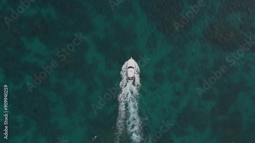 Drone top down overview tracking follows yacht speedboat in green blue sandy reef waters photo