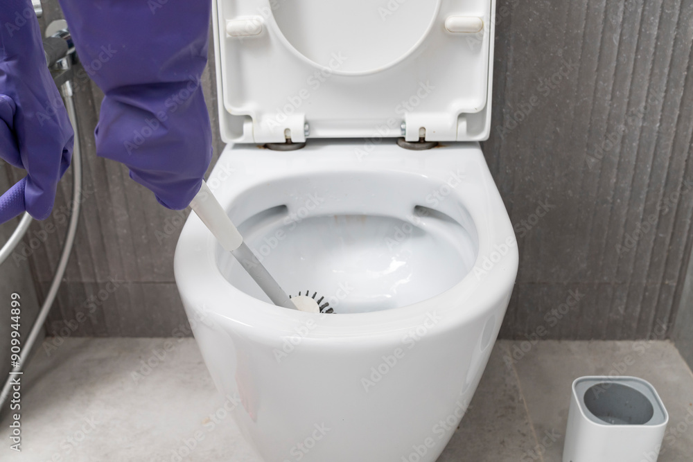 Сlose-up shot of a man in rubber gloves cleaning a toilet using a special cleaning product and a brush Сlose-up shot of a man in rubber gloves cleaning a toilet using a special cleaning product and a brush