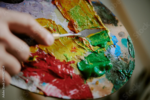 Extreme closeup of unrecognizable artist mixing oil or acrylic paints on wooden palette with use of palette knife photo