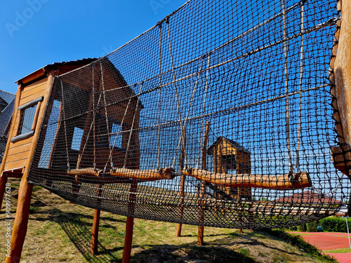 netted tunnel made of ropes. visitor child, crawling through the labyrinth. stainless steel slide. urban parl mebo school yard wooden attraction castle
 photo