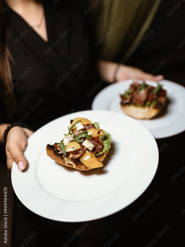 cute girl is holding two beautiful white plates, each with a sandwich with juicy ham and fresh greens, in a cozy and nice restaurant cute girl is holding two beautiful white plates, each with a sandwich with juicy ham and fresh greens, in a cozy and nice restaurant