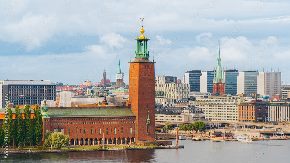 The town hall of Stockholm, Sweden, tourists and people in the park after a summer rain storm, downtown city in the background. Cloudy with the sun peaking trough The town hall of Stockholm, Sweden, tourists and people in the park after a summer rain storm, downtown city in the background. Cloudy with the sun peaking trough