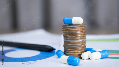 Blue and white capsules on and around a stack of coins, meaning health insurance, medical expenses and medicine, finance, saving money, business, financial and medical healthcare concepts.