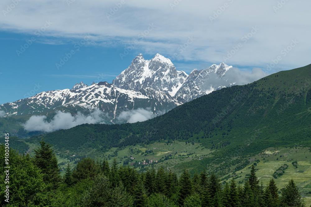 In sunny weather, green fields and snowy hills. Snowy mountain landscapes in spring in Svaneti.Magnificent mountain landscapes of Georgia. In sunny weather, green fields and snowy hills. Snowy mountain landscapes in spring in Svaneti.Magnificent mountain landscapes of Georgia.