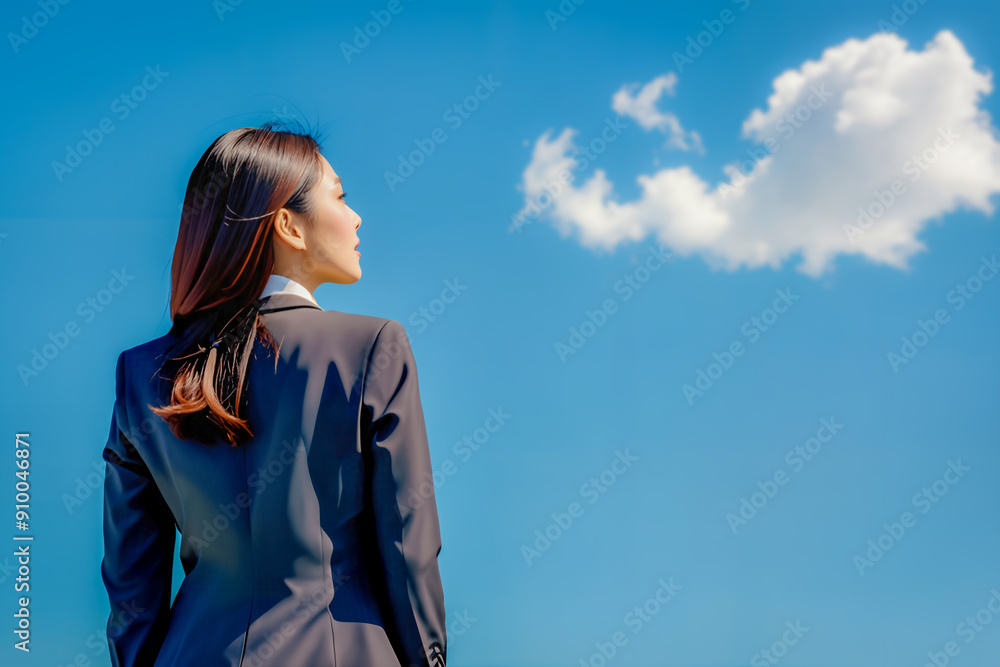 Back view of businesswoman in a suit looking up at a clear blue sky. Back view of businesswoman in a suit looking up at a clear blue sky.