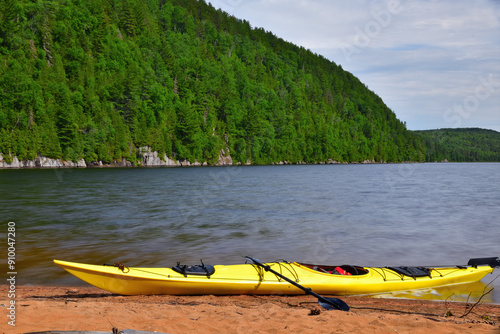 Yellow sea kayak at sand beach on the Wapizagonke lake. Canada Park La Mauricie, Quebec, Canada. Summer paddling day. Long exposure. photo