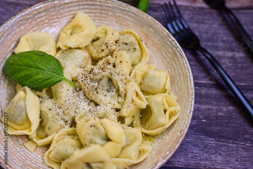 Home made vegetarian italian Tortellini with pesto genovese filled with spinach and parmesan cheese, decorated with fresh basil