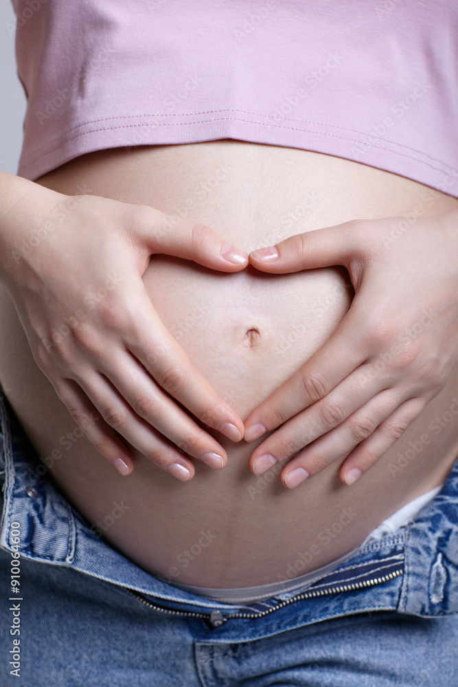 Female on 6th month of pregnancy. Woman touching with hands her naked belly and shows heart sign. Female on 6th month of pregnancy. Woman touching with hands her naked belly and shows heart sign.
