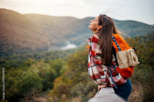 Young woman breathing pure air in a forest. Young woman hiking and going camping in nature. Person with backpack walking in the forest. Trekker breathing fresh air in the top of a mountain