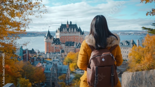 Travel destination: Quebec City, Canada. Asian woman tourist strolling around and taking in the views of the St. Lawrence River and Chateau Frontenac Castle—a well-liked autumn travel destination photo