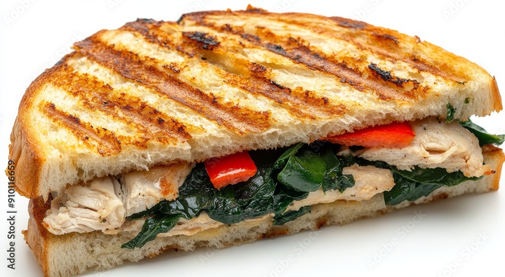 In this panini, pesto chicken is topped with roasted red peppers, mozzarella, and spinach on a bed of spinach on a transparent backdrop. In this panini, pesto chicken is topped with roasted red peppers, mozzarella, and spinach on a bed of spinach on a transparent backdrop.