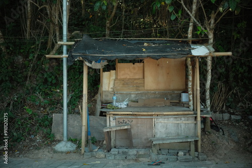 An abandoned and damaged small bamboo hut in a quiet area far from the city with wild plants surrounding it photo