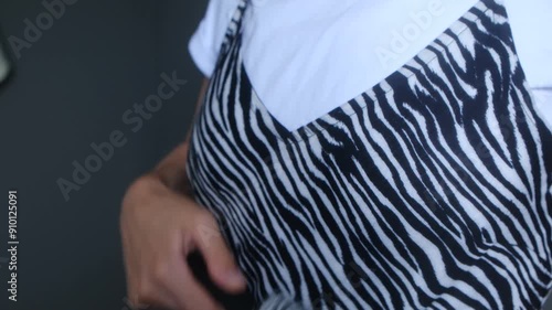 Woman uses sticky roller to remove unwanted fur and hair from stylish dress zebra print. Close up. Female runs lint roller meticulously leaving clean fabric. young lady is going on date