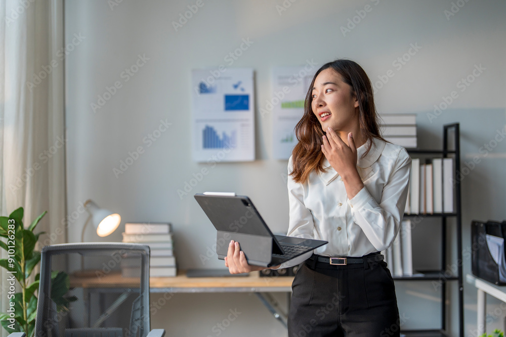 Young asian businesswoman holding tablet and thinking in modern office