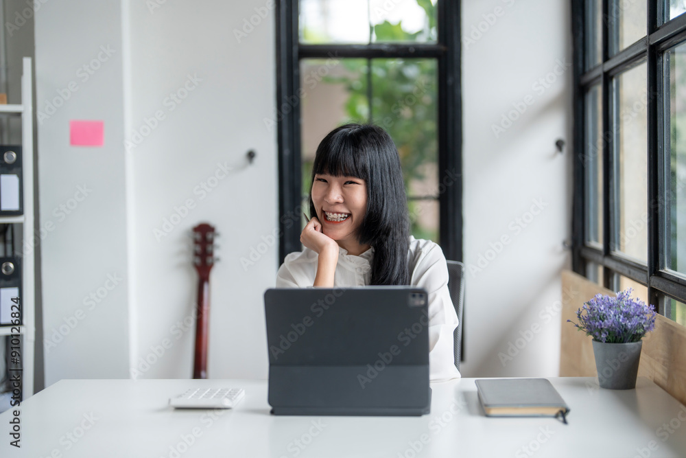 Asian woman working from home office using digital tablet smiling at work Asian woman working from home office using digital tablet smiling at work