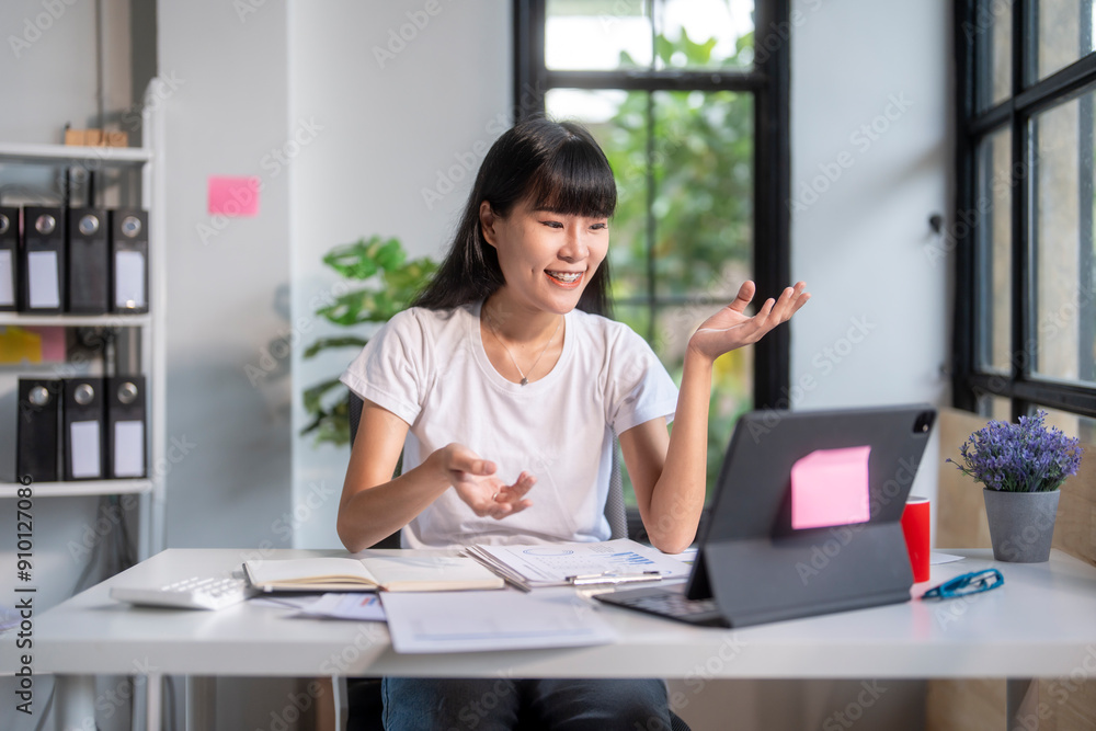 Asian businesswoman video conferencing on tablet and gesturing while working from home office Asian businesswoman video conferencing on tablet and gesturing while working from home office