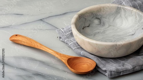 Wooden Spoon Beside Marble Bowl on Gray Cloth Set Against Smooth Surface