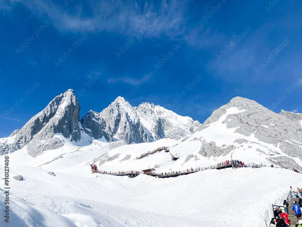 Fototapeta premium Panoramal nature view Jade Dragon Snow Mountain with soft white cloud on blue sky and soft sunlight in morning, Shangri-La City or Xiang Ge Le La at Yunnan, China