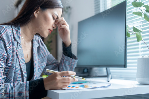 Businesswoman suffering from headache while working on financial report in office