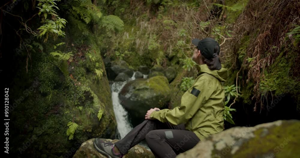 Woman sit near waterfall in jungle forest on Madeira island. Travel tourism, freedom and active lifestyle concept Woman sit near waterfall in jungle forest on Madeira island. Travel tourism, freedom and active lifestyle concept