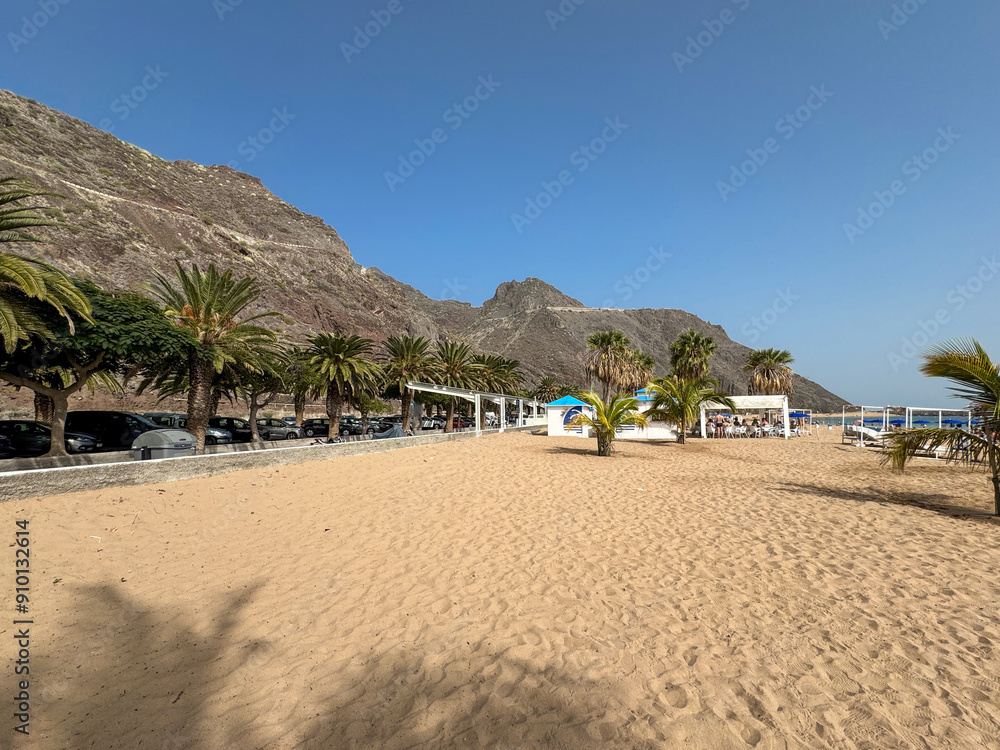 Scenic Teresitas Beach in the North of Tenerife Island next to San Andres town. Palm Trees and Mountains Under Clear Blue Sky. Scenic Teresitas Beach in the North of Tenerife Island next to San Andres town. Palm Trees and Mountains Under Clear Blue Sky.