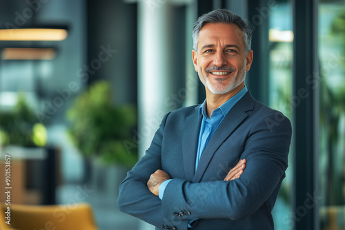 Wallpaper Mural Confident mature man in a blue suit standing with arms crossed in a modern office. Professional indoor portrait photography. Business and leadership concept. Design for banner, poster, header Torontodigital.ca