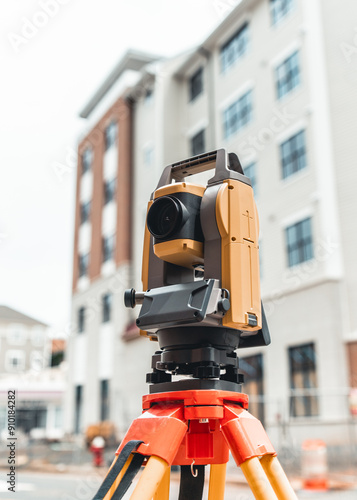 land surveying total station instrument on a tripod with a building in the background