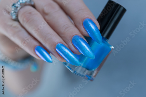 Female hand with long nails and bright light blue and silver manicure	 photo