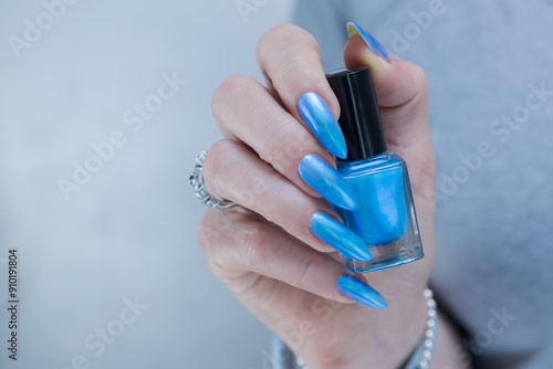 Female hand with long nails and bright light blue and silver manicure	 photo