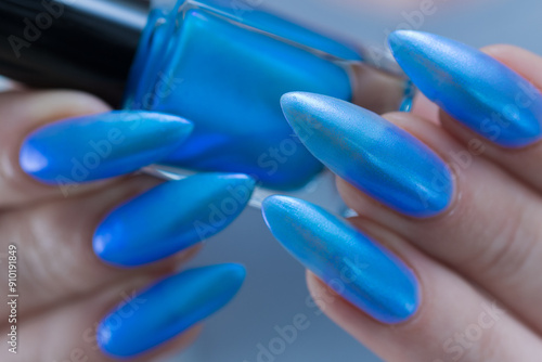 Female hand with long nails and bright light blue and silver manicure	 photo