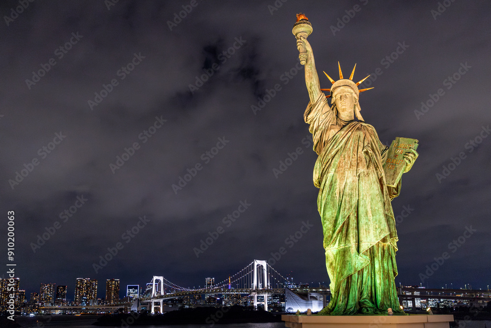 Fototapeta premium The statue of liberty is standing tall in odaiba, tokyo at night