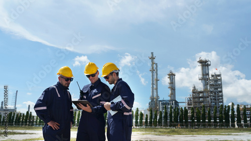 Three Male professional expert engineer standing talking tablet working inspecting maintenance system and training oil refinery at column tank oil of Petrochemistry industry Teamwork concept