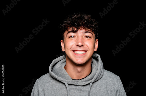 Portrait of a smiling Caucasian man in his 20s wearing a sweatshirt against a dark background.