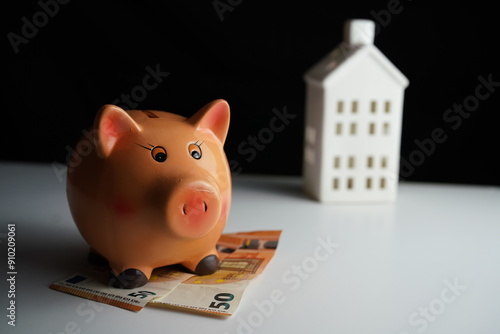 Wallpaper Mural Horizontal photo of a piggy bank next to several euro bills in front of a residential building as a concept of saving for the purchase of a home Torontodigital.ca