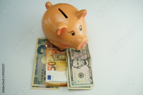 Wallpaper Mural top view of a piggy bank on several dollar, euro and yen bills as a currency saving concept Torontodigital.ca